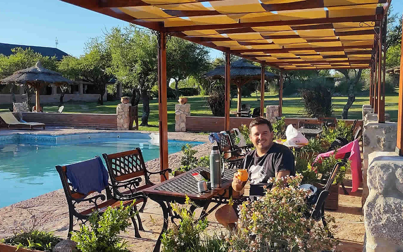 Pileta al aire libre con pérgola, reposeras y las sierras de fondo